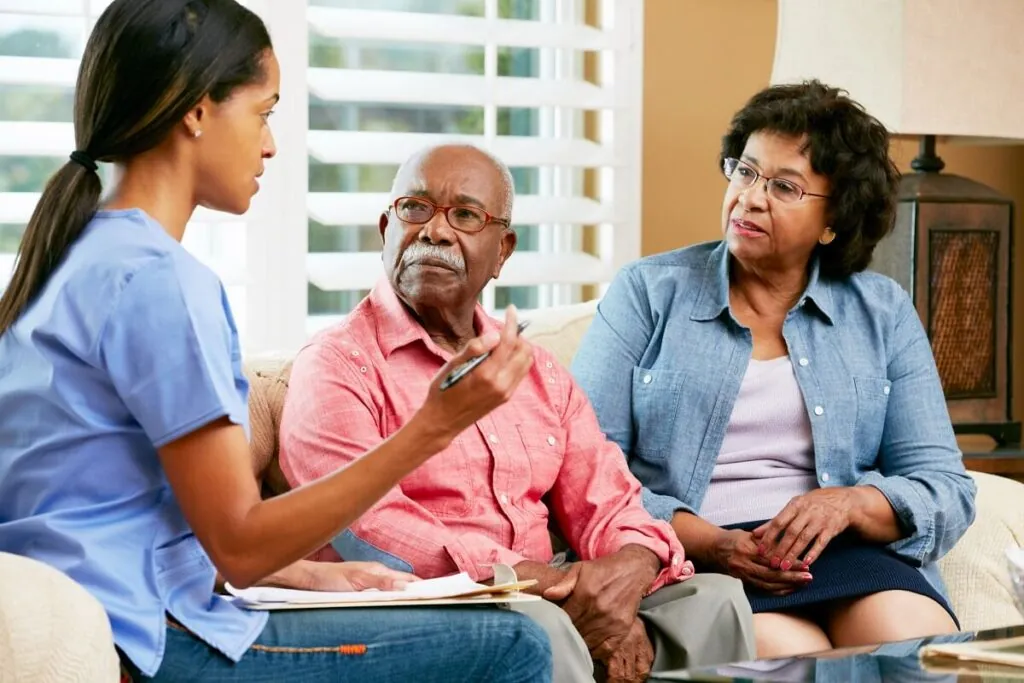 A nurse explaining a care plan to an older couple on their sofa