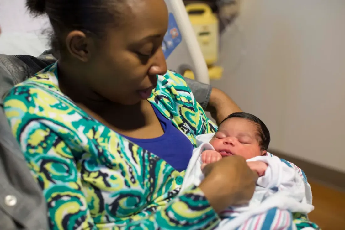 A new mother looking down at her sleeping newborn
