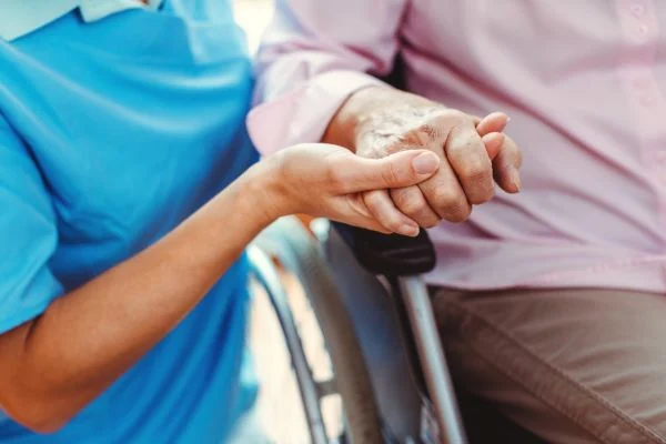 A nurse gently holding an elderly patient’s hand